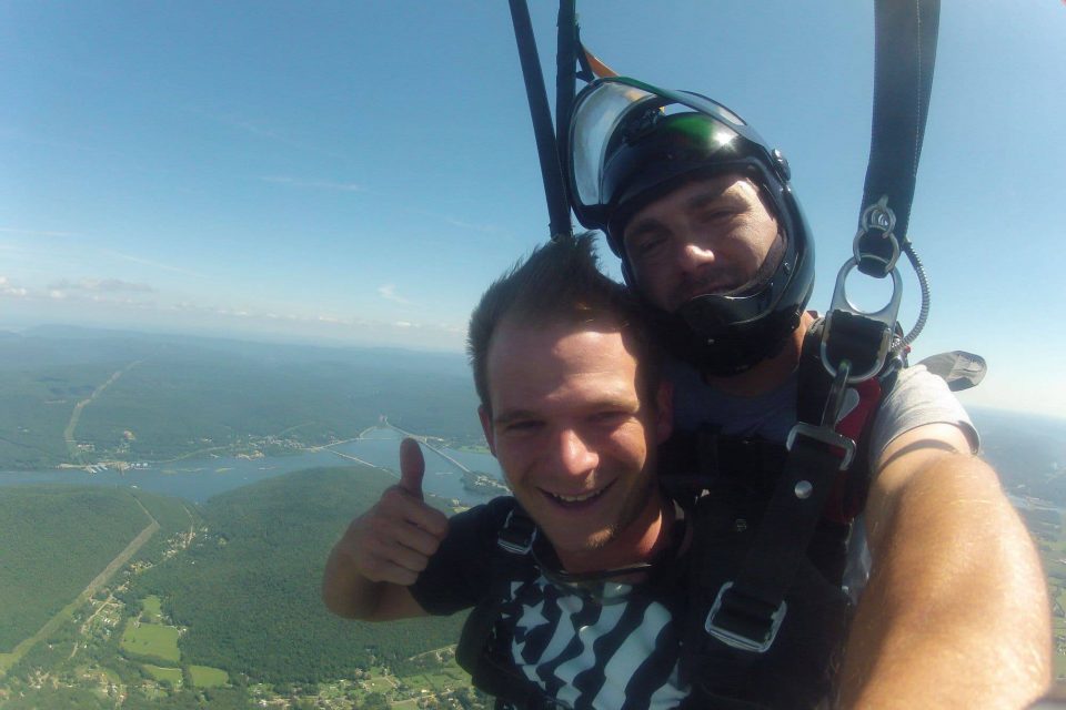 Tandem skydiver giving a thumbs up while enjoying the canopy ride down to landing