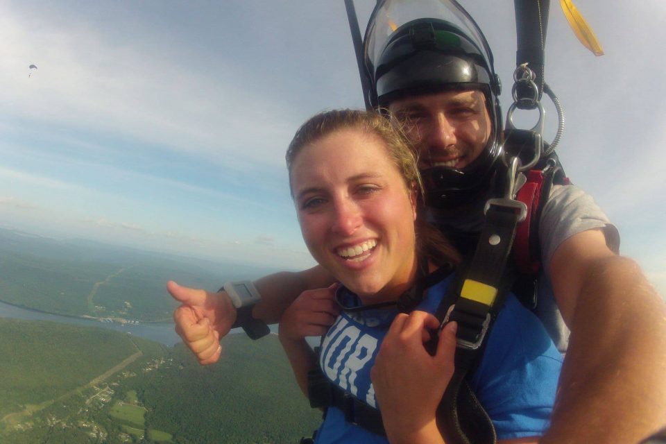 Female tandem skydiver wearing blue shirt under canopy