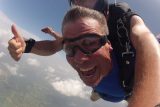 Skydiver enjoying free fall with tandem instructor giving thumbs up