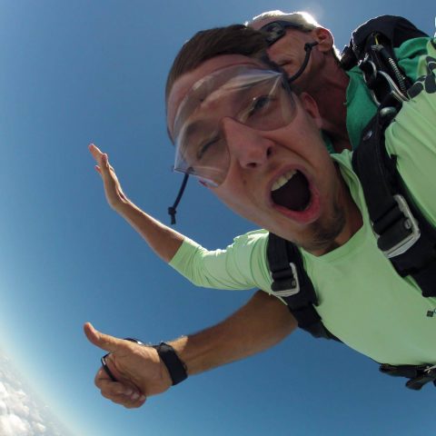 Man in green shirt enjoying free fall with Chattanooga Skydiving Company tandem instructor