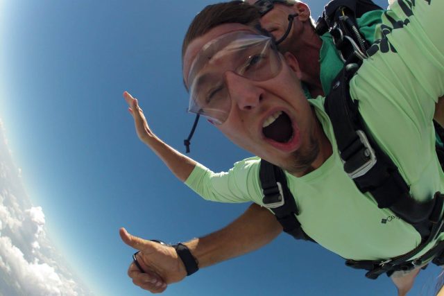 Man in green shirt enjoying free fall with Chattanooga Skydiving Company tandem instructor