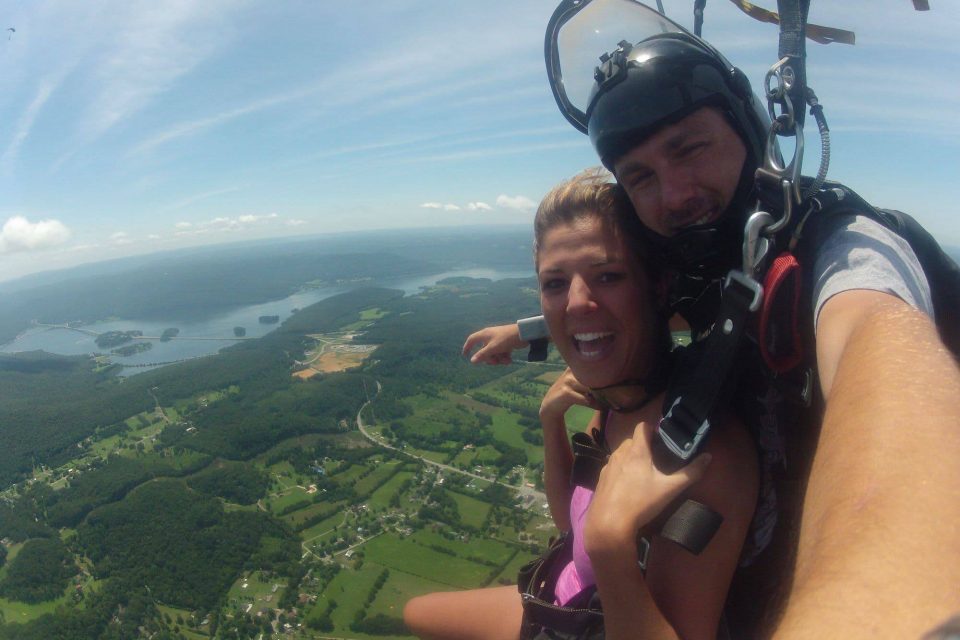 Smiling women wearing pink shirt enjoys the canopy ride down with Chattanooga Skydiving Company tandem instructor