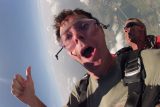 Man in green shirt gives thumbs up during free fall at Chattanooga Skydiving Company