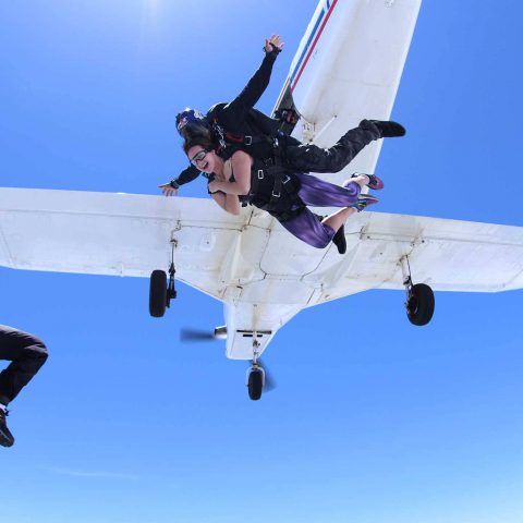 Women wearing purple plants smiles after jumping from the Chattanooga Skydiving Company airplane and into free fall