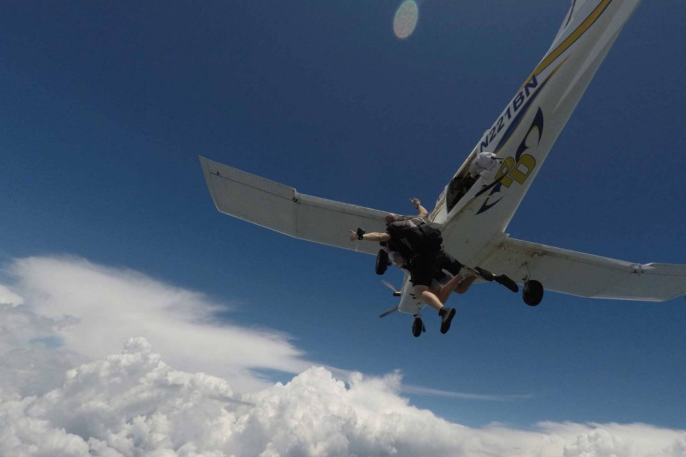 Tandem skydiver leaps from aircraft into free fall