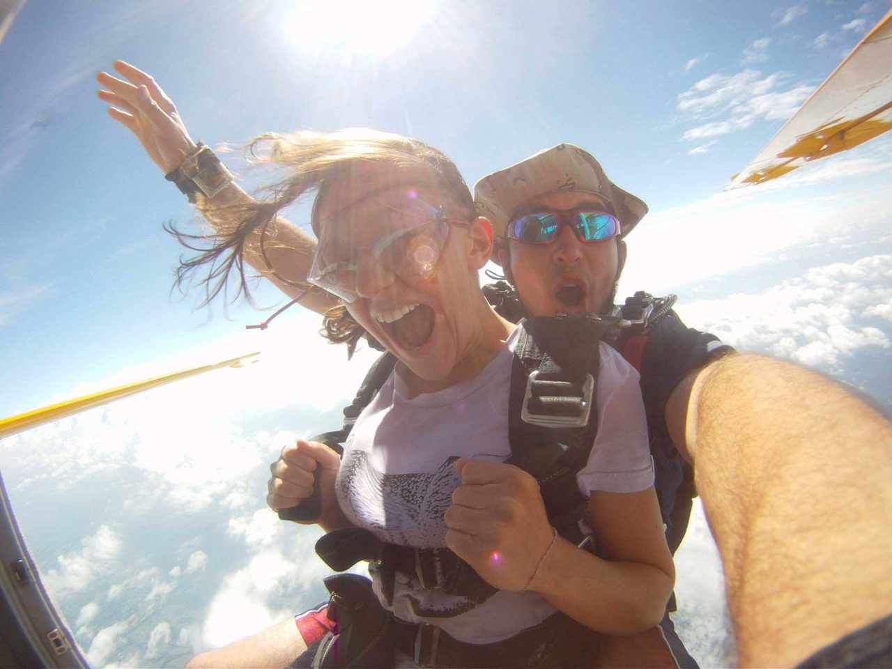 Women smiles while jumping into free fall with tandem instructor