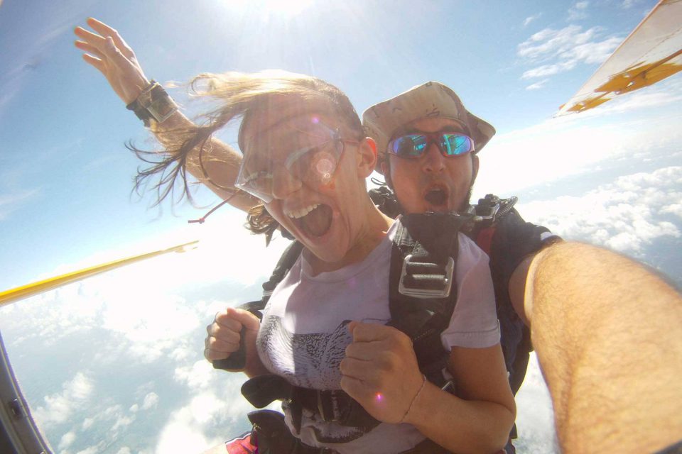 Women smiles while jumping into free fall with tandem instructor