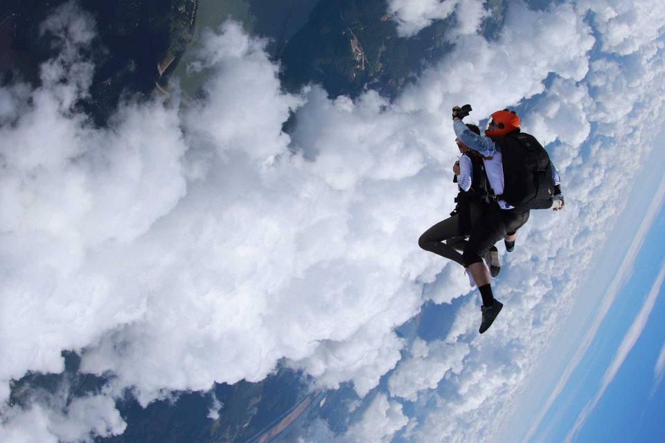 Tandem skydiver enjoying free fall surrounded by white clouds and blue skies